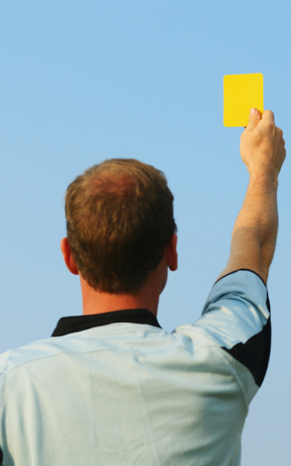 Referee holding up a yellow card, symbolising challenging unfair holiday park rules