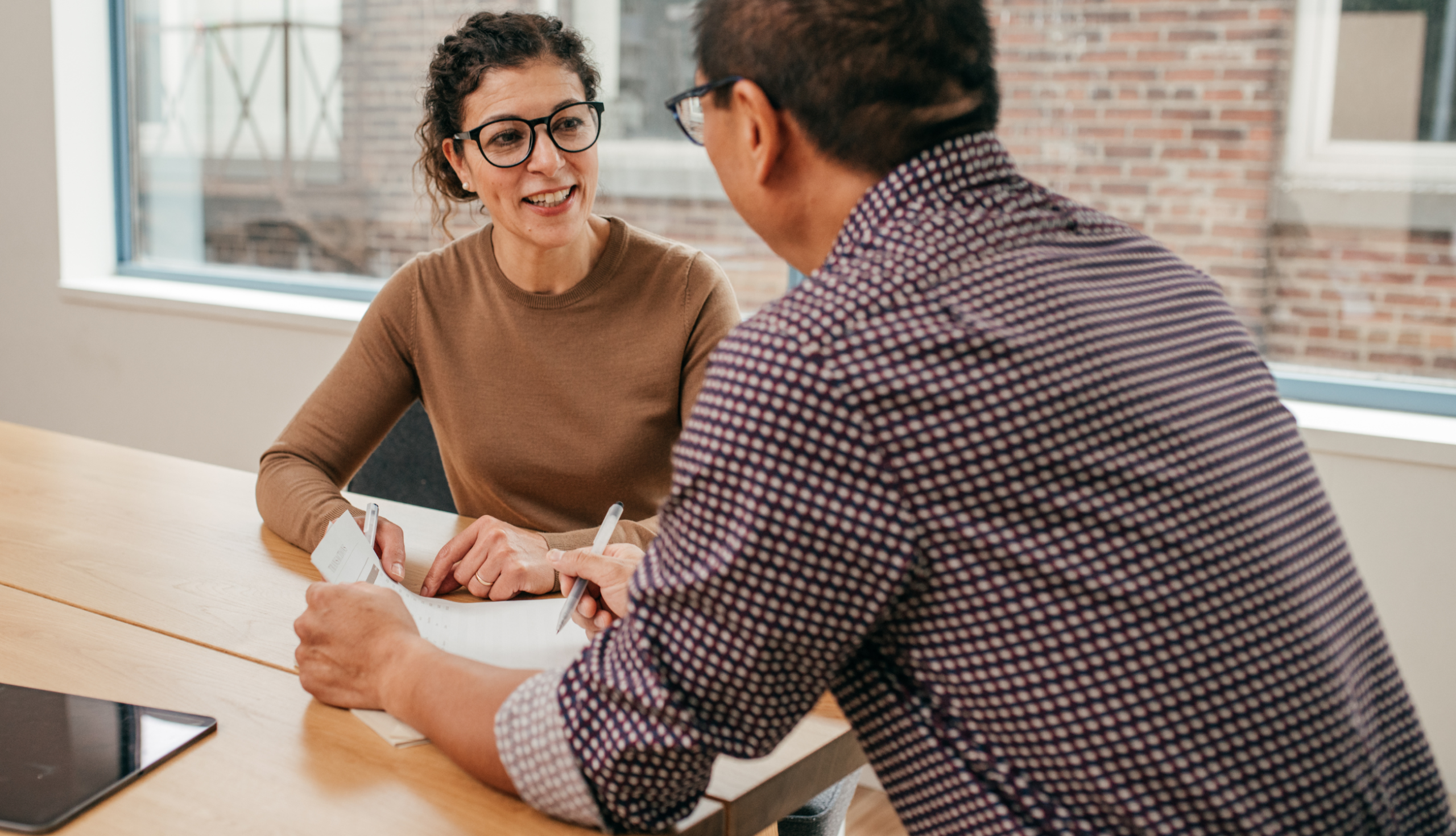 Caregiver assists two elderly women knitting