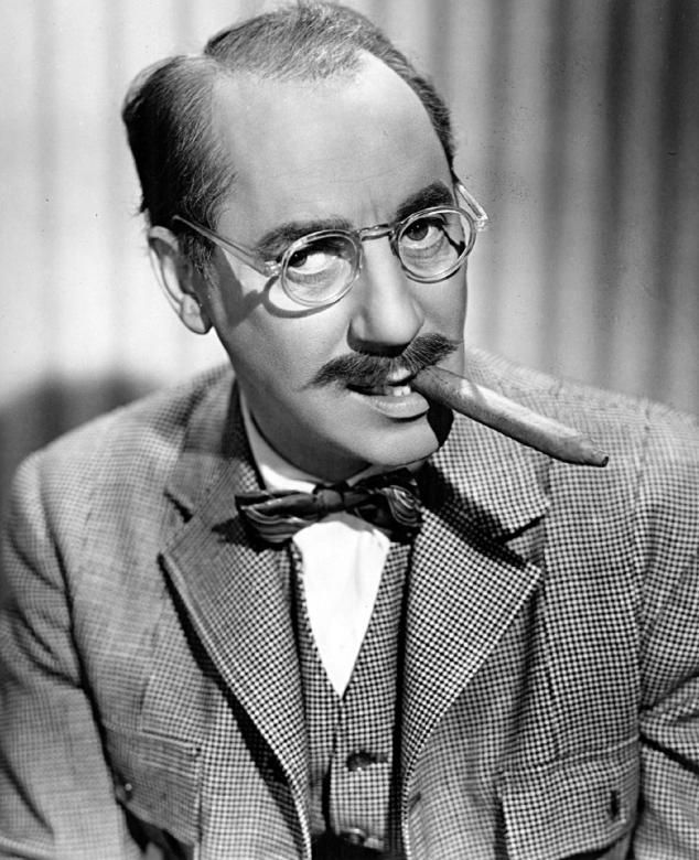 Portrait of Groucho Marx wearing glasses and holding a cigar